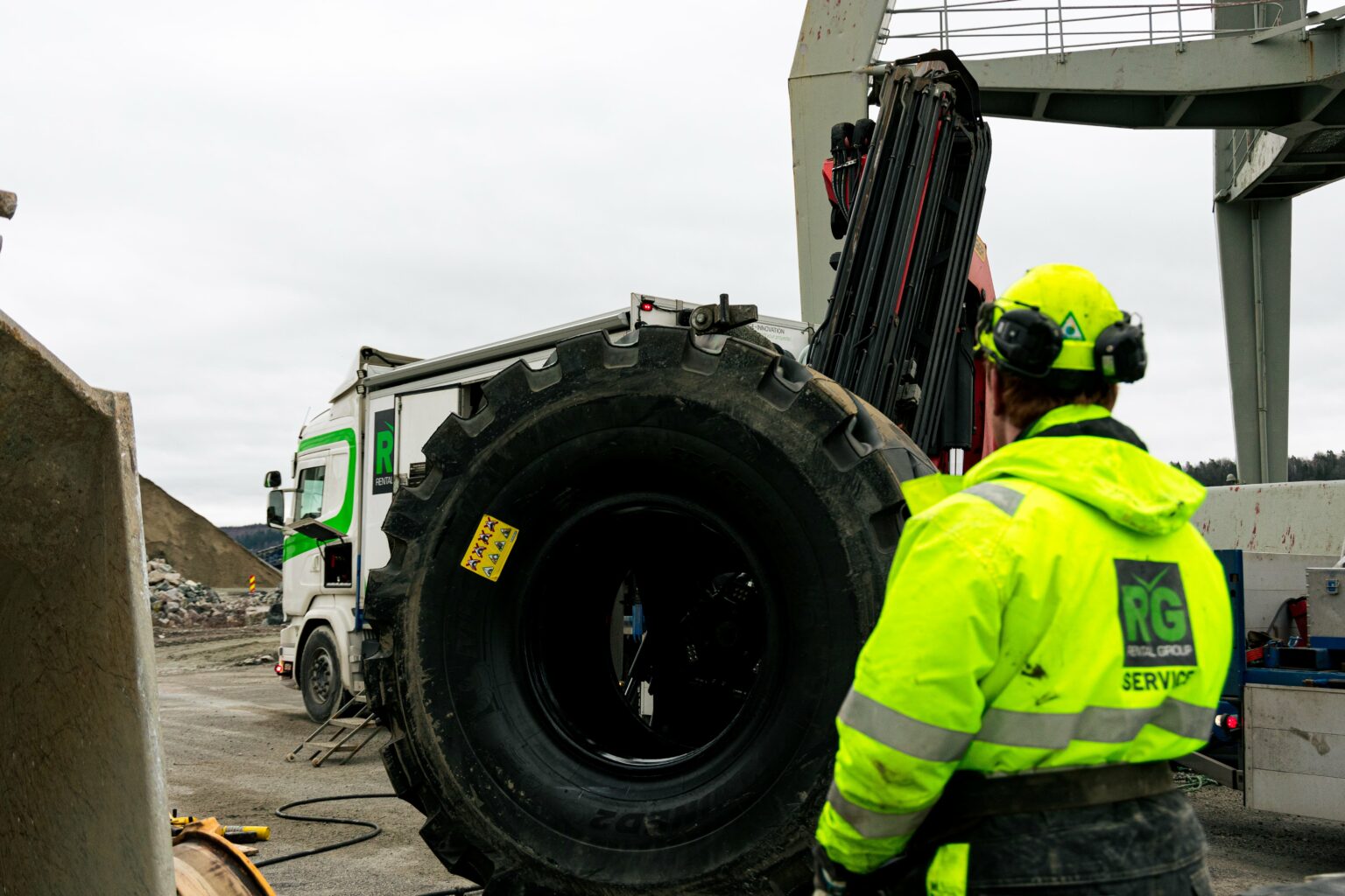 Mekaniker fra Rental Group styrer et stort anleggsdekk som henger i kranen på servicebilen